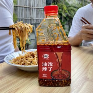 น้ำมันพริกจีนชุ่ยหงษ์ขวดแดงบนโต๊ะกินคู่กับผัดเส้นข้าว